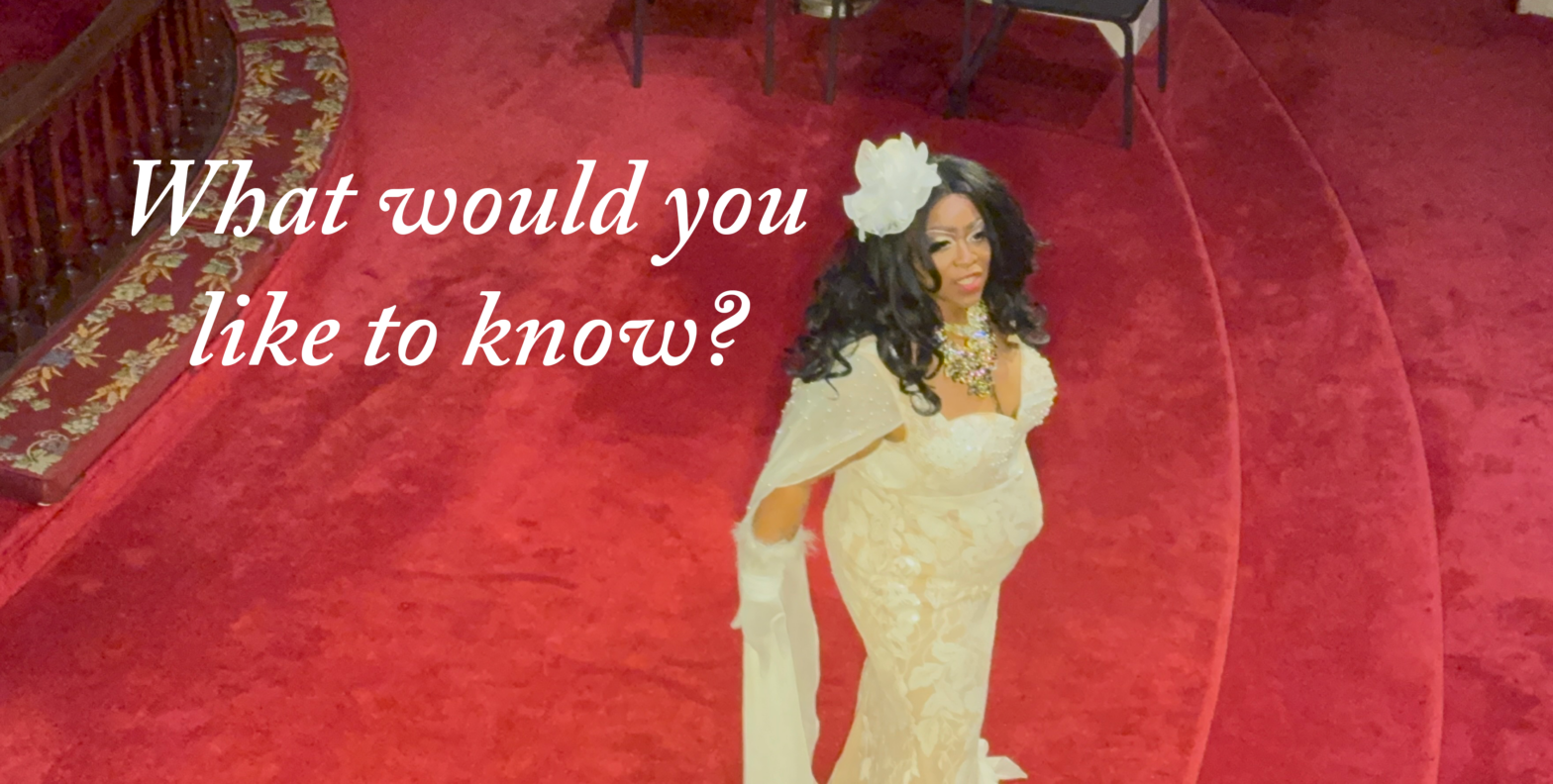A picture of the Drag Performer, Sybill Disobedience, performing on a red carpet in the Episcopalian Church in Portsmouth. The text overlay reads "What would you like to know?"
